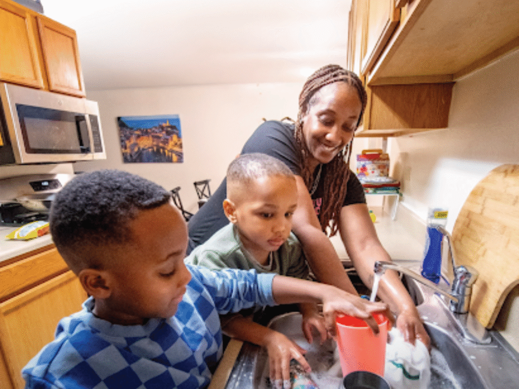 Mother washing dishes with her sons