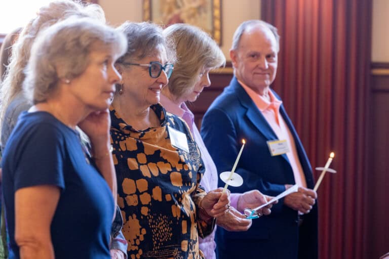 Cheryl Marita and seniors smiling and holding candles during the mass at the adoptee reunion.