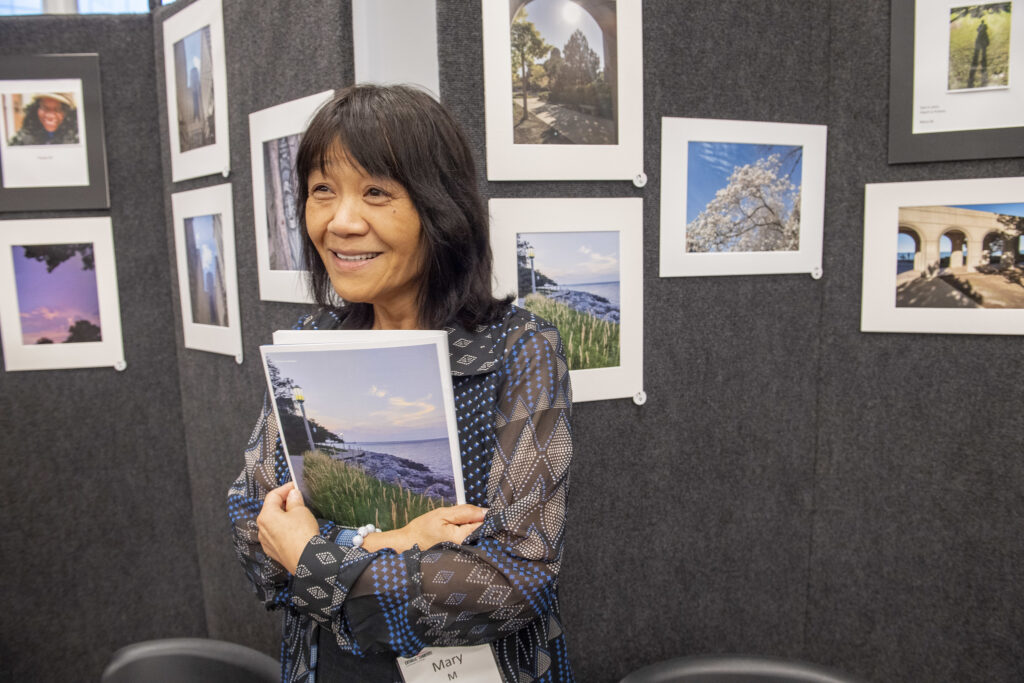 Mary M standing infront of her shots at Visions of my Life: 2025 Photo exhibit