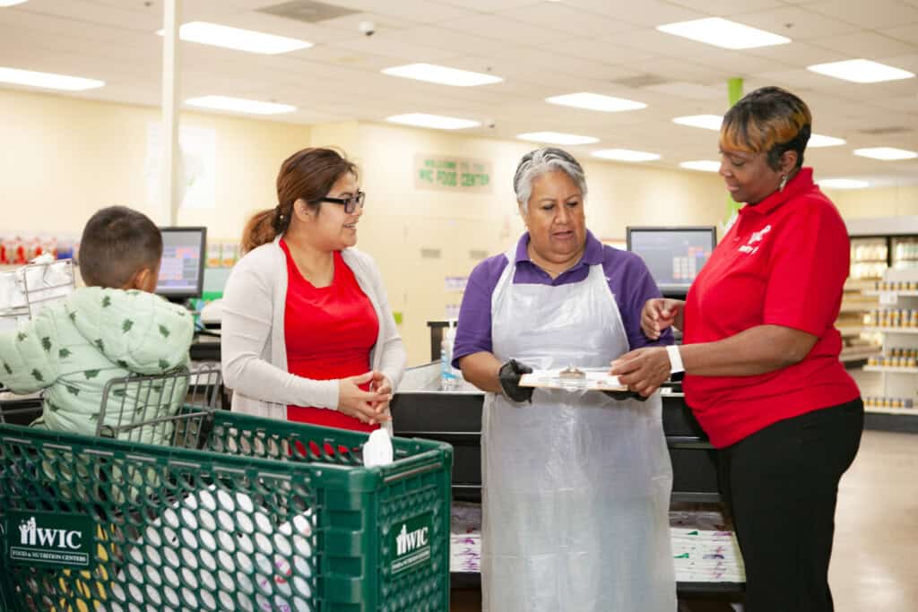 Employee/volunteers/customers interacting at WIC grocery store