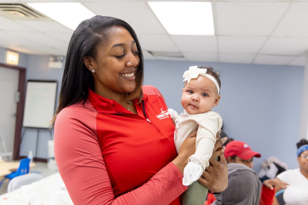 Doula Keiona Johnson Smiling holding a newborn baby