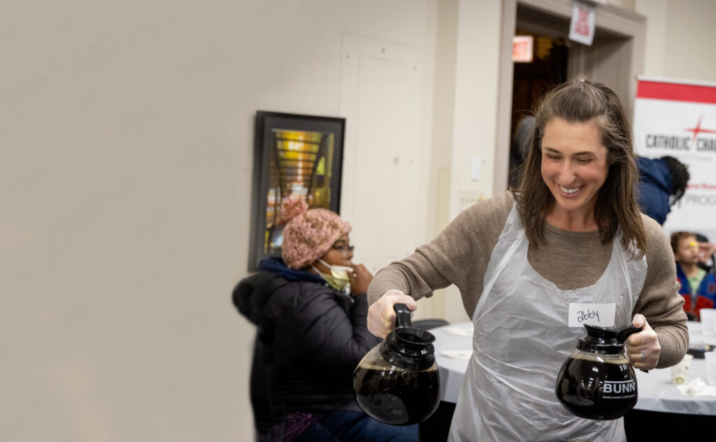Volunteer, Abby, serving coffee to community meal attendees
