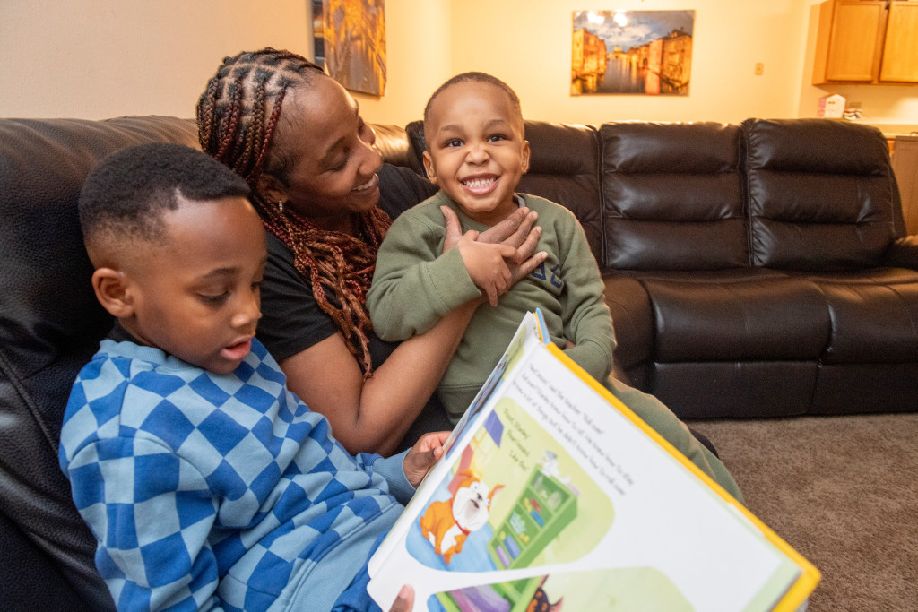 Mother interacting with her children as one of her sons reads a book