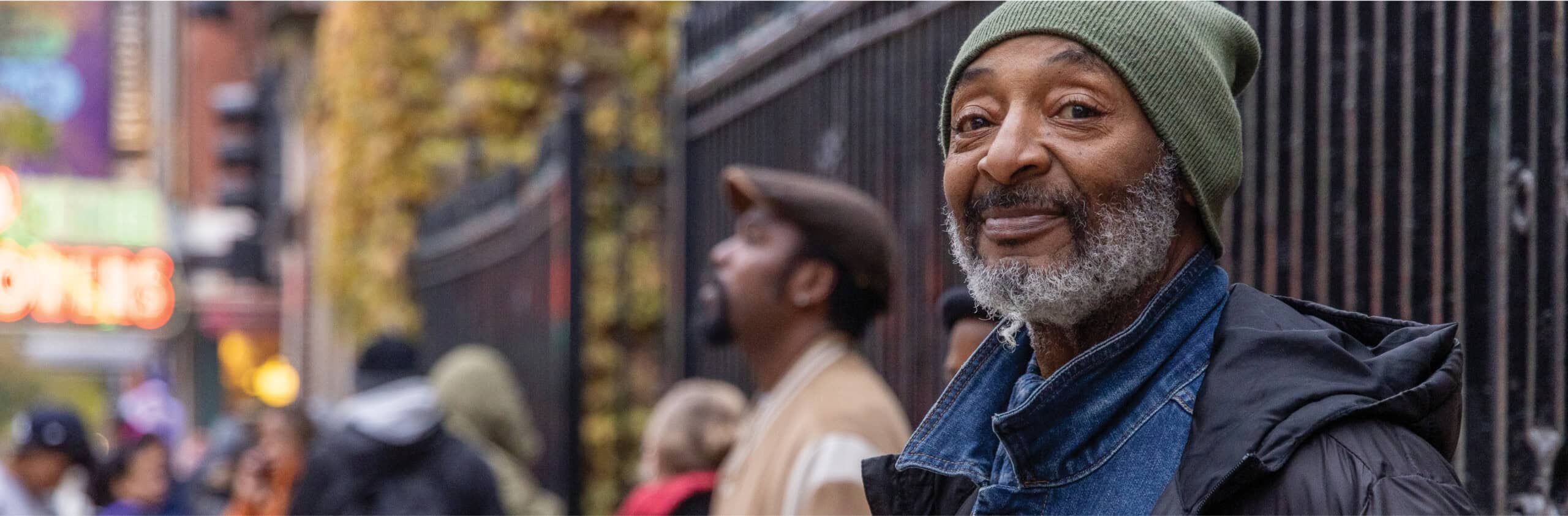 Senior smiling waiting in line outside of Catholic Charities banner