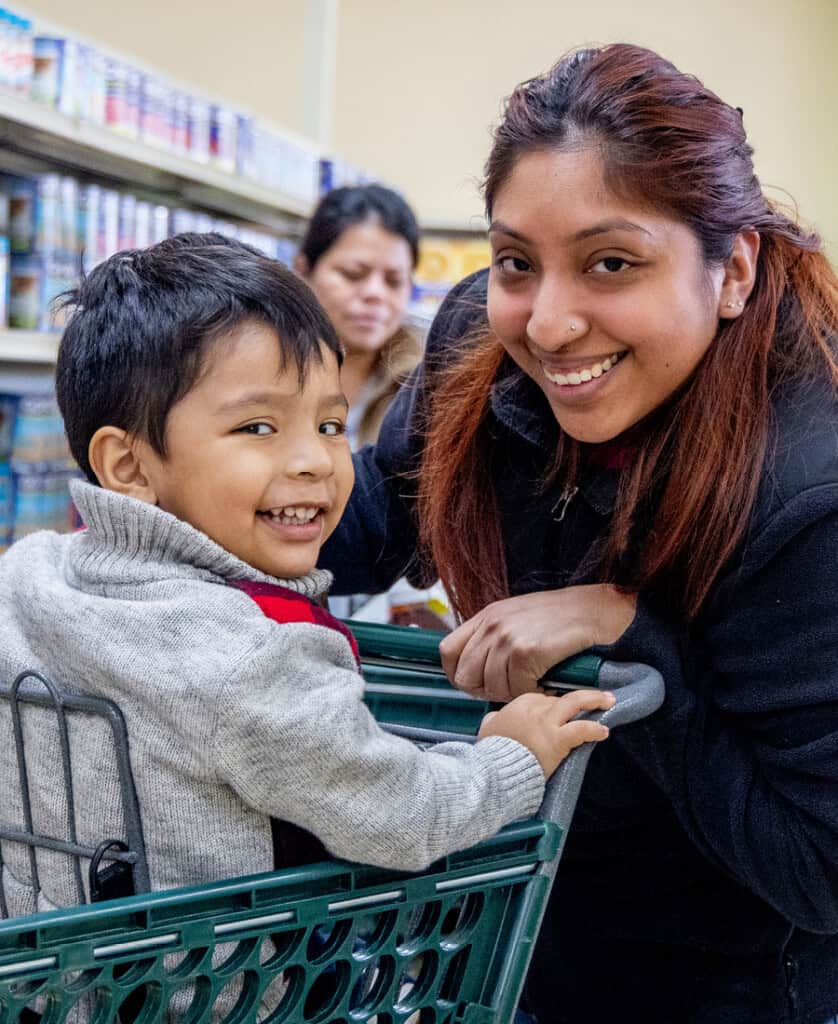 Woman pushing her son in grocery store cart at Food Pantry