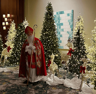 Saint Nicholas standing in front of Christmas trees at the St. Nicholas Ball 2025